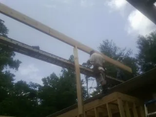 Carpenter setting a ridge beam over a new addition frame — Ice Dam Removal by Roofing Brothers in Heflin