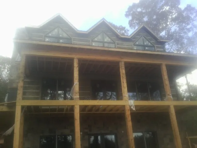 Dormers and porch framing on a large log home under construction — Roof Coating work by our crew in Heflin