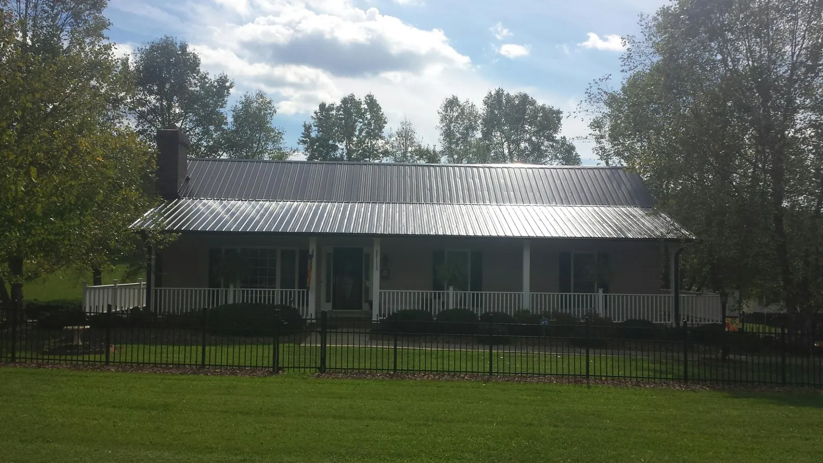 Gray metal roof on a brick ranch with a full width front porch — Gutter Guard Installation work by our crew in Heflin