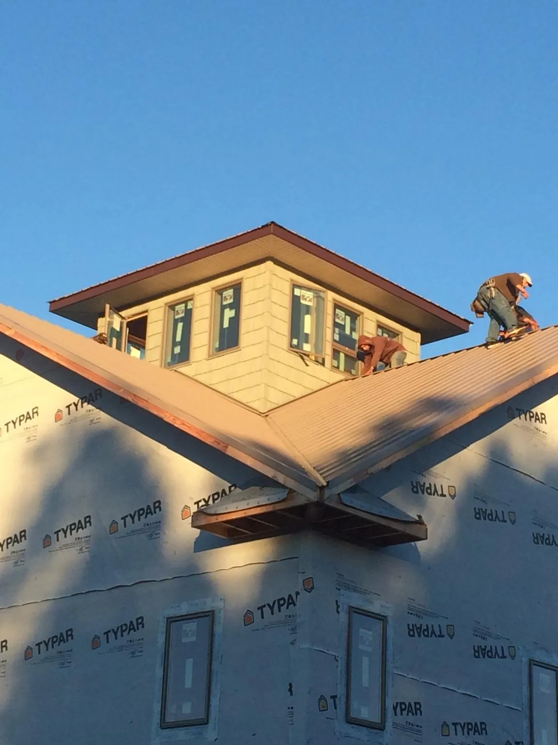 Roofers working around a rooftop cupola on a new metal roof at sunset — Roof Waterproofing in Heflin by Roofing Brothers